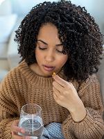 Woman taking a supplement with a glass of water