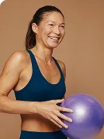 Woman smiling and holding an exercise ball